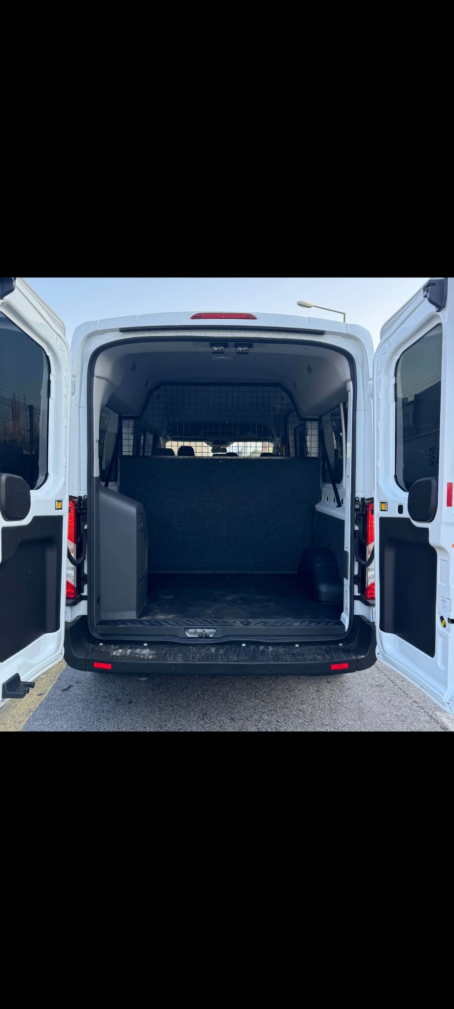 Ford Transit com portas traseiras abertas e compartimento de carga limpo.